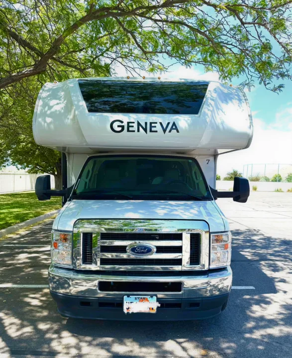 Front of a white Geneva Ford RV rental parked under a leafy tree on a sunny day.. Thor Geneva 2022
