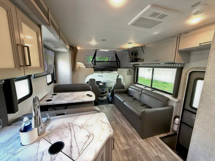 Spacious RV rental interior featuring a modern kitchen, dinette, comfortable sofa, and a cab-over bunk bed.. Thor Geneva 2022
