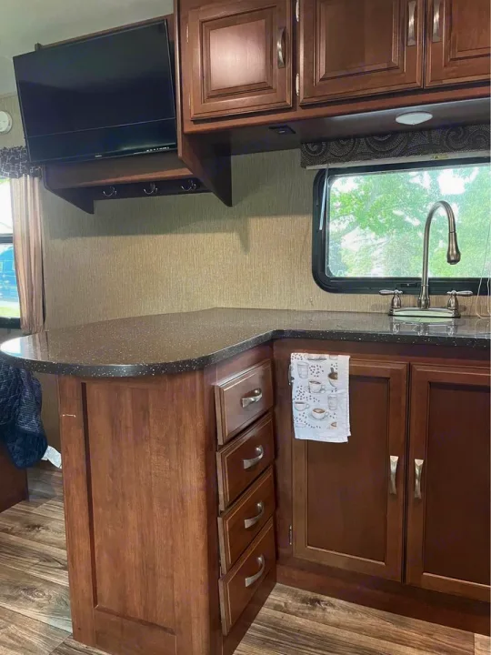 Clean RV rental kitchen: features modern cabinets, sink, counter space, and a TV. Perfect for your next adventure.. Keystone RV Passport Elite 2017