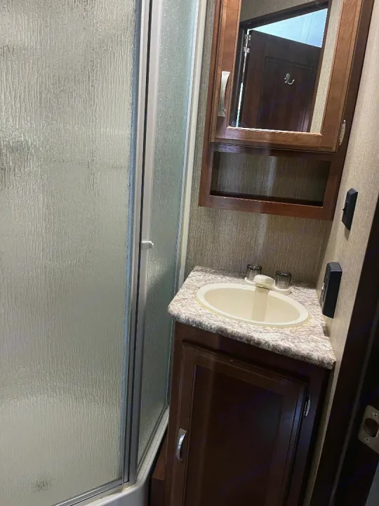 Inside an RV rental bathroom: compact shower and vanity with sink. Enjoy comfort on the road!. Keystone RV Passport Elite 2017