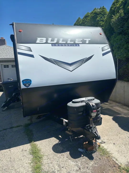 Front view of a black and white Bullet Crossfire travel trailer, ready for RV rental adventures. Parked on a sunny day.. Keystone RV Bullet Crossfire 2024