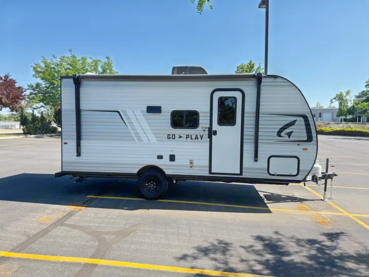 Explore with this light gray travel trailer, ready for rv rental. Parked in a sunny lot. Go Play!. Wayfinder RV Go Play 19BH 2025