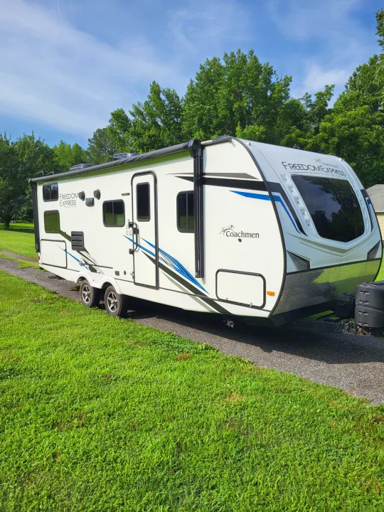Coachmen Freedom Express RV rental, a white travel trailer parked on gravel with green trees and blue sky.. Coachmen Freedom Express Ultra Lite 257BHS 2023