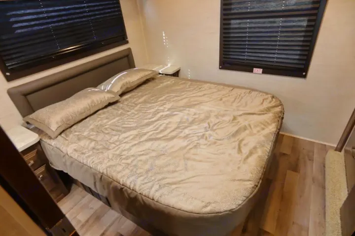 Cozy RV rental bedroom with a queen bed, neutral decor, and window blinds. Ready for your next adventure.. Jayco Redhawk 2021