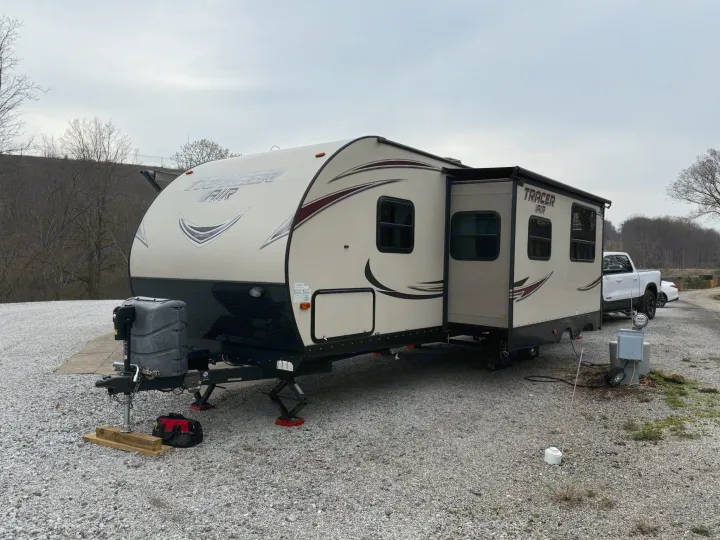 RV rental: A travel trailer is parked on a gravel site with its slide-out extended and hookups.. Forest River Tracer Air 2016