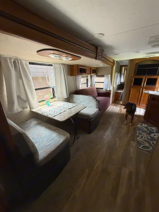 Inside this inviting RV rental: a dining area, cozy seating, and a dog on hardwood floors. Your mobile home away from home!. Forest River Tracer Air 2016