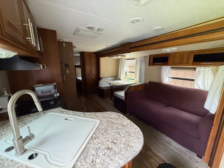 Spacious RV rental interior featuring a full kitchen, comfortable sofa, and dining area. Perfect for your next adventure!. Forest River Tracer Air 2016