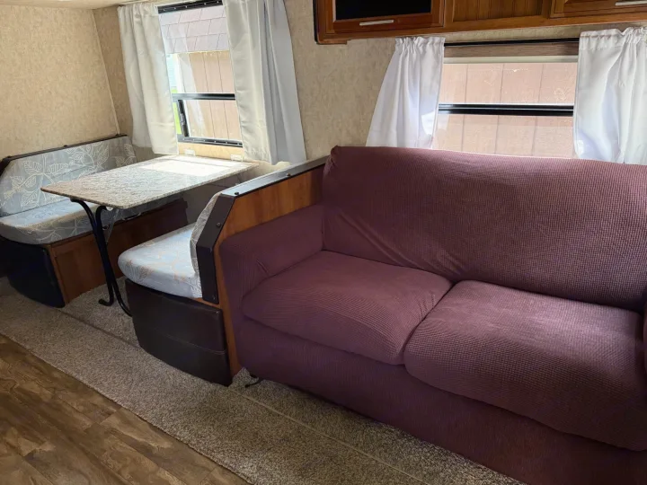 Inside an RV rental: a comfortable living space with a bright dinette area and a spacious burgundy sofa. Ideal for your next trip.. Forest River Tracer Air 2016