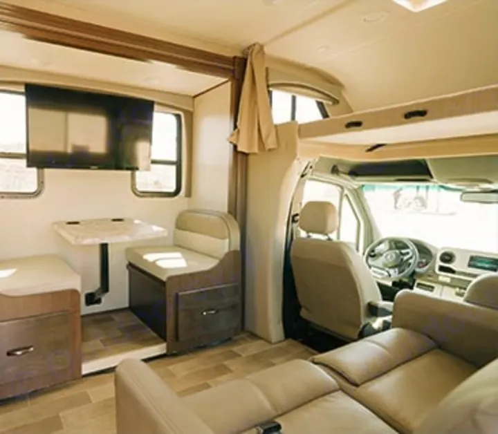 Experience the modern, spacious interior of an RV rental, featuring a dinette, TV, overhead bunk, and comfortable living area.. Thor Chateau Sprinter 2020