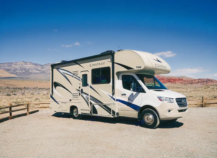 A beige Chateau RV rental parked in a desert landscape with mountains under a clear sky, ready for adventure.. Thor Chateau Sprinter 2020