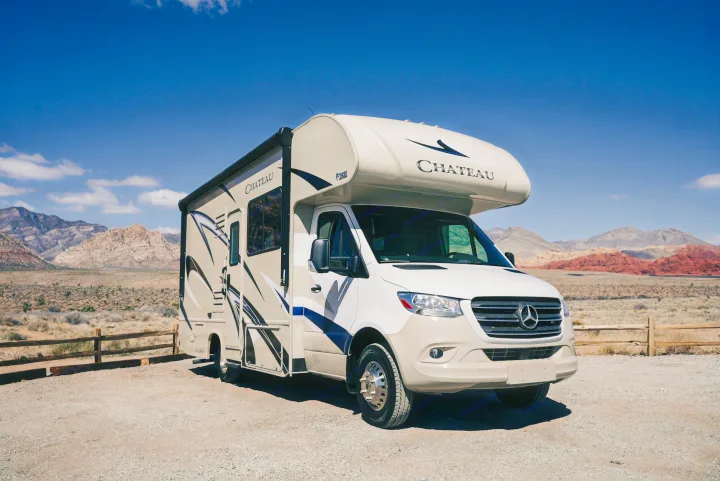 This Chateau RV rental, a Class C motorhome, is parked on a gravel lot in a stunning desert mountain landscape.. Thor Chateau Sprinter 2020