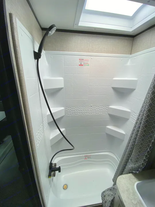 RV rental: Compact white shower stall with handheld head, built-in shelves, tub base, and skylight.. Jayco Jay Flight SLX 2022