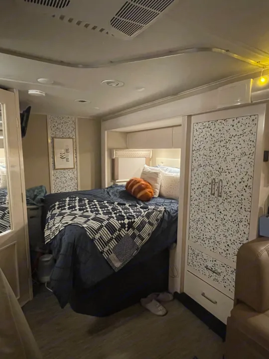 Cozy RV rental bedroom with a comfortable bed, overhead storage, and a stylish speckled cabinet.. Renegade Custom Coaches Vienna 2021