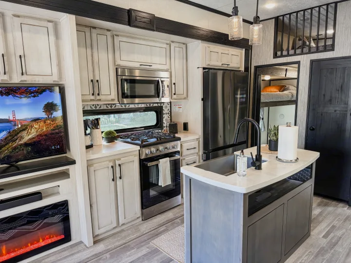 Spacious RV rental interior featuring a modern kitchen, living area with TV/fireplace, and cozy bunk beds.. Durango Gold 2023