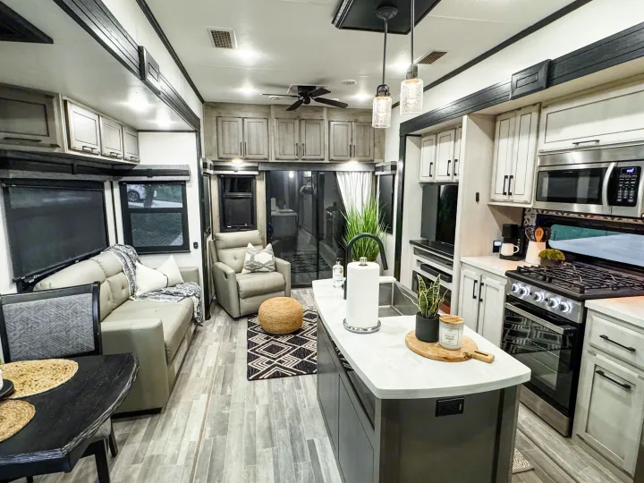 Spacious RV rental interior featuring a modern kitchen island, living area sofa, & stylish decor for mobile living.. Durango Gold 2023