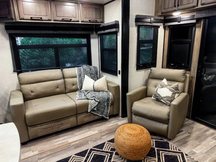 Comfortable RV rental living space featuring modern gray furniture, overhead cabinets, and large windows.. Durango Gold 2023