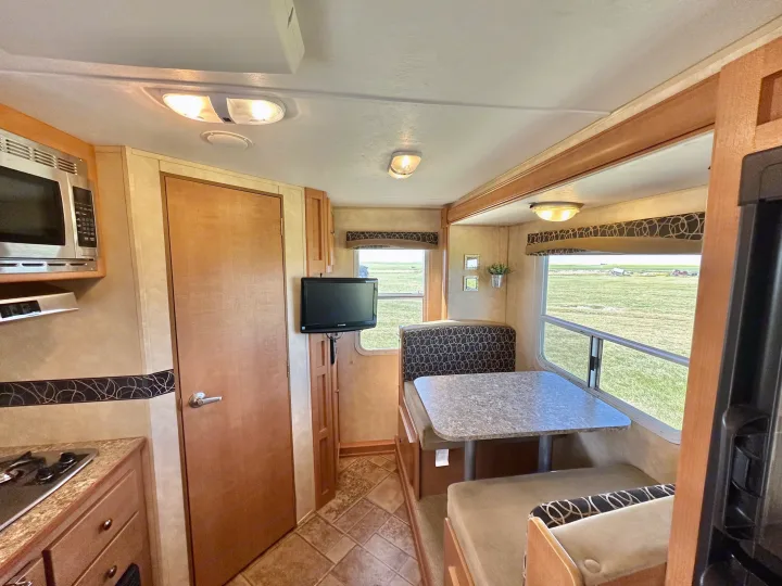 Inside a modern RV rental, featuring a full kitchen, dining area, and TV. Enjoy panoramic views of the countryside.. Cruiser RV Fun Finder X 2011