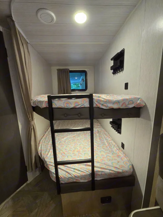 This RV rental features comfy bunk beds with bright rainbow sheets, overhead lighting, and storage for a fun trip.. Forest River Salem Cruise Lite Platinum 2023