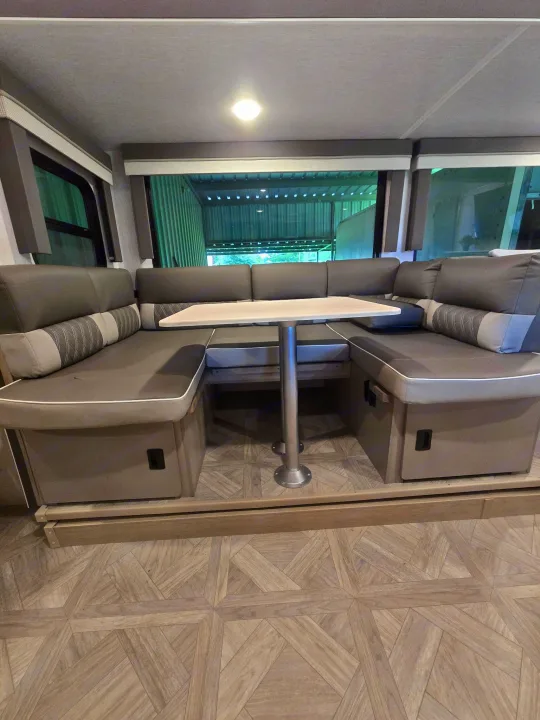 Cozy U-shaped dinette with table in an RV rental, offering comfortable gray seating, perfect for meals & relaxation.. Forest River Salem Cruise Lite Platinum 2023