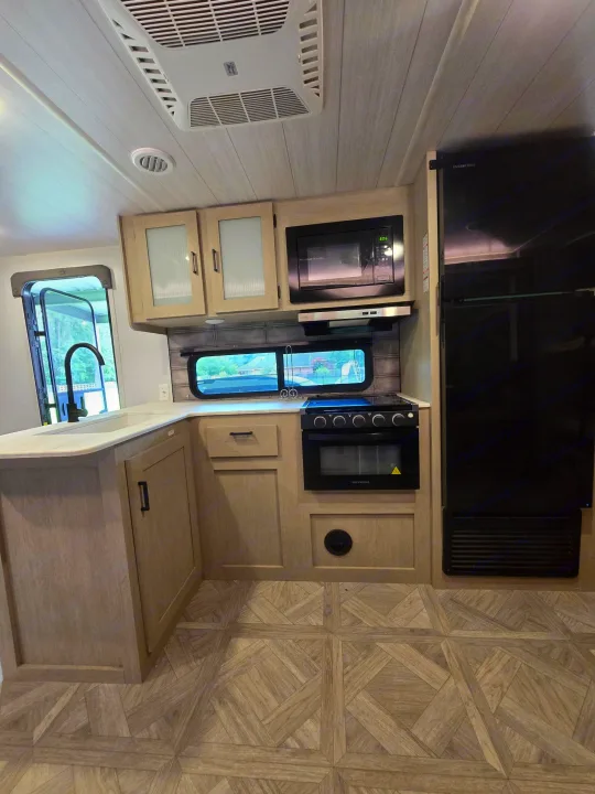 Spacious RV rental kitchen: modern sink, microwave, stove, fridge, and wood-look flooring. Ideal for road trips!. Forest River Salem Cruise Lite Platinum 2023
