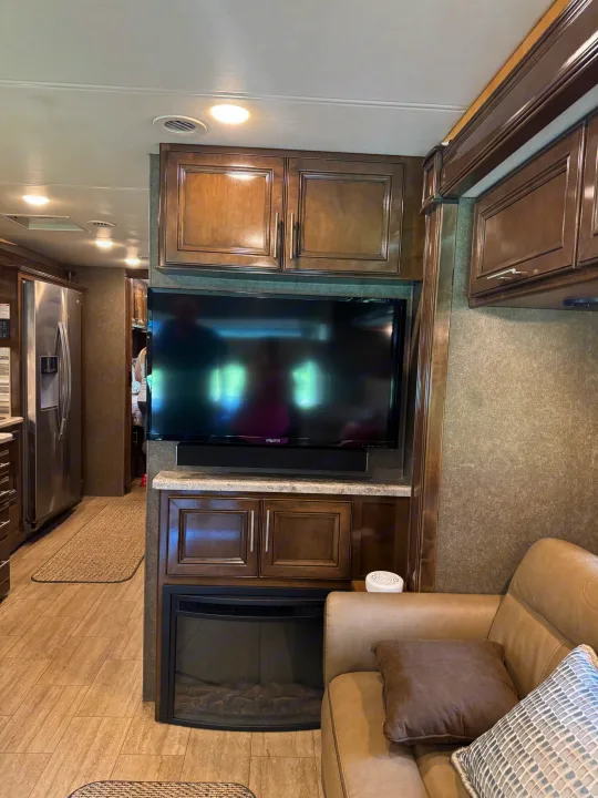 Explore this comfortable RV rental interior: living area with TV, electric fireplace, sofa, and a full kitchen.. Thor Challenger 2020