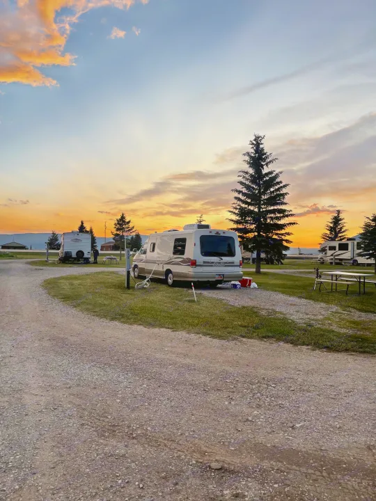 Camper van at an RV park campsite, silhouetted against a vibrant sunset sky. Ideal for an RV rental getaway.. Eurovan Camper Rialta 2000