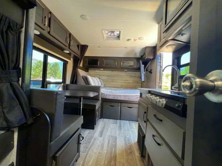 Step inside a modern RV rental, featuring a sleek dinette, well-equipped kitchen, and cozy bed for your travel adventures.. Jayco Jay Feather Micro 2021
