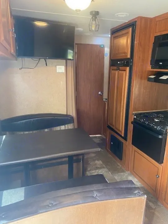 Spacious RV rental interior featuring a dinette, wall-mounted TV, and full kitchen with fridge/stove. Perfect for travel!. Jayco Jay Flight 2013