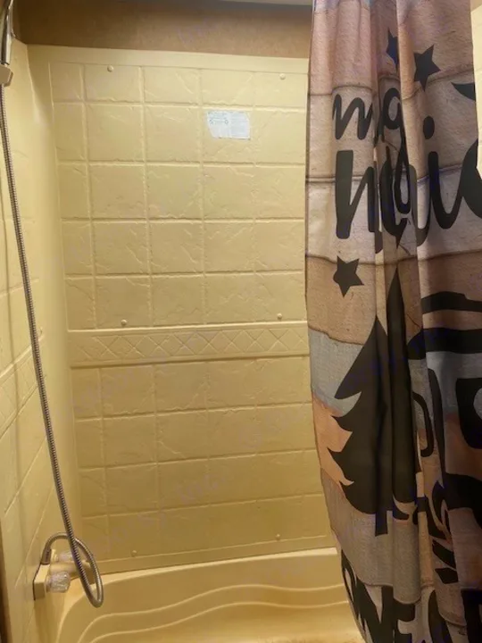 Inside an RV rental: a practical beige shower stall with a flexible hose and festive curtain.. Jayco Jay Flight 2013