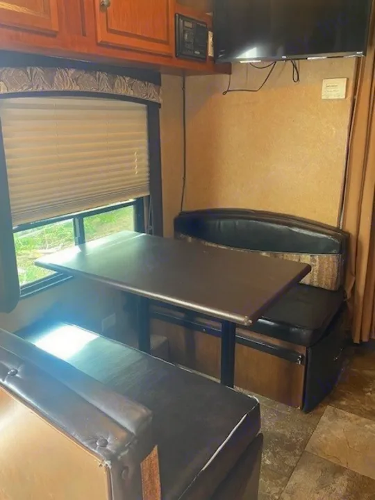 RV rental interior: dinette with dark benches, table, window, and wall-mounted TV for comfortable living.. Jayco Jay Flight 2013
