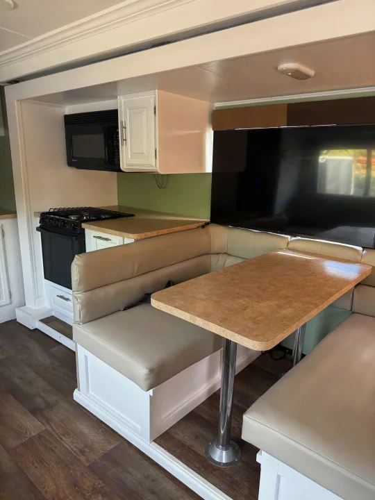 Modern RV rental interior: kitchen with stove, microwave, and cozy dining booth with TV.. FR3 FR3 Motorhome 2016