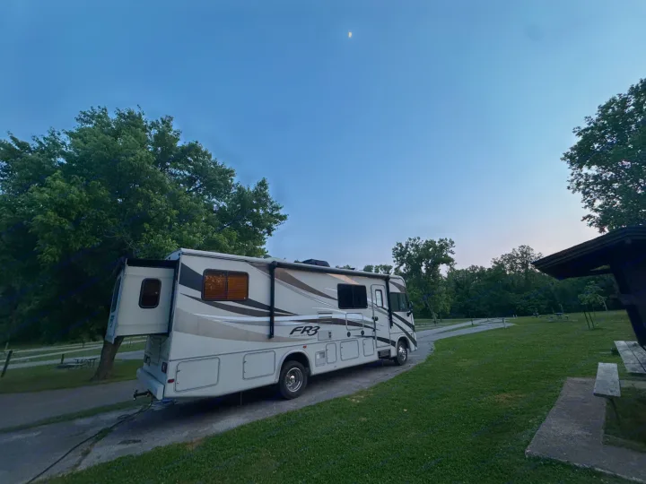 RV rental parked with slide-outs extended in a wooded campground at dusk, with a visible crescent moon.. FR3 FR3 Motorhome 2016