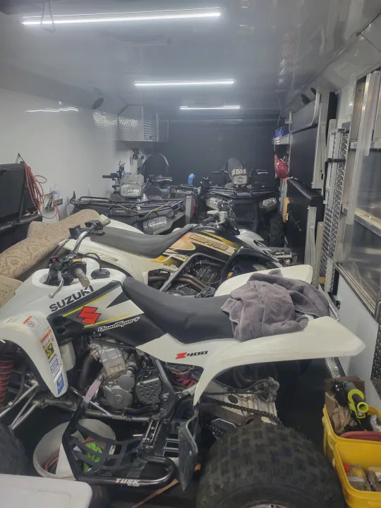 Several ATVs neatly packed inside an RV rental toy hauler, ready for off-road adventures and powersports fun.. Trails West RPM Toy Hauler 2023