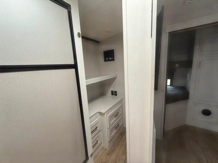 Inside an RV rental, showing a fridge, built-in storage, laundry hookups, and a glimpse of the bunk beds. Modern and functional.. Astoria Astoria Trailer 2022