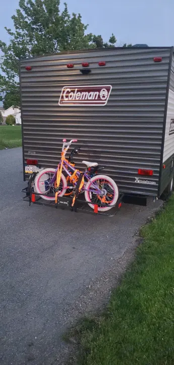 An RV rental, a Coleman travel trailer, with two colorful bicycles secured to a rear bike rack.. Dutchmen Coleman Lantern LT 2021