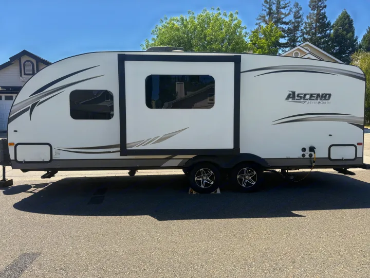 Spacious white travel trailer with slide-out extended, perfect for an RV rental adventure, parked on pavement.. Evergreen RV Ascend 2015