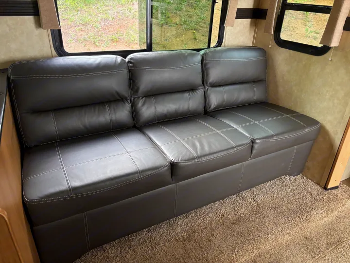 Spacious dark gray sofa inside an RV rental, offering comfortable seating with views out the windows. Ideal for travel.. Cruiser Rv Corp 280Bunkhouse Cruiser 2015