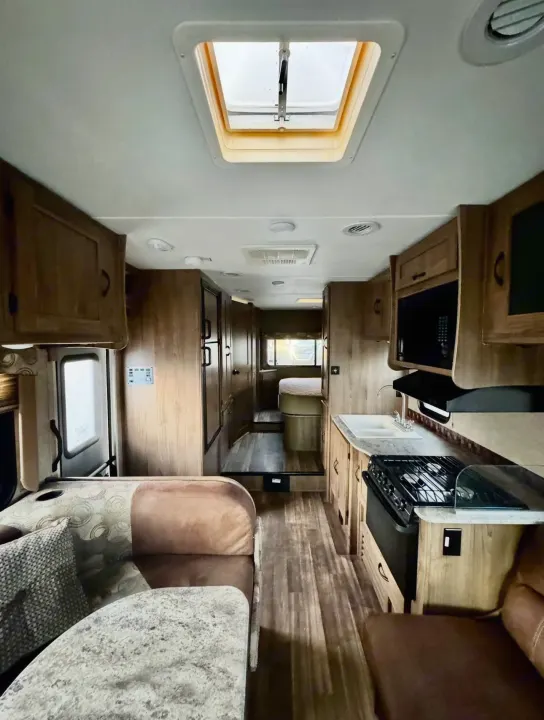 Bright RV rental interior featuring a full kitchen, comfy seating, and rear sleeping area. Note the overhead skylight.. Forest River Coachmen Freelander 2017