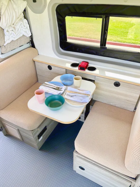 Modern rv rental interior showing a dining nook with set table, benches, and ample storage. Perfect for travel!. Winnebago Solis Pocket 2022