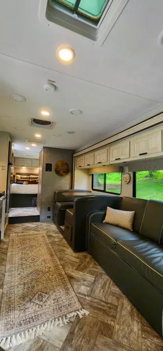 Spacious RV rental interior with living area, dinette, and bedroom, featuring light herringbone flooring and modern cabinets.. Forest River Sunseeker LE 2022