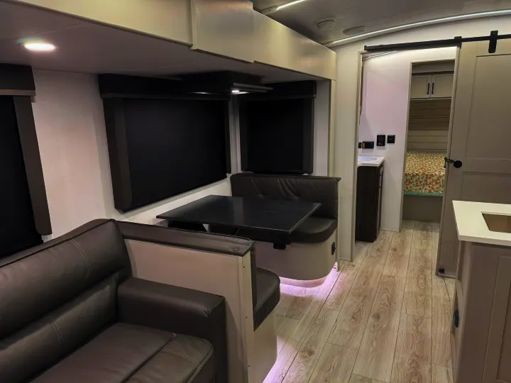 Explore this modern rv rental's interior: a comfortable dinette & sofa in the living space, with bedroom access.. Keystone Outback 291BH 2025