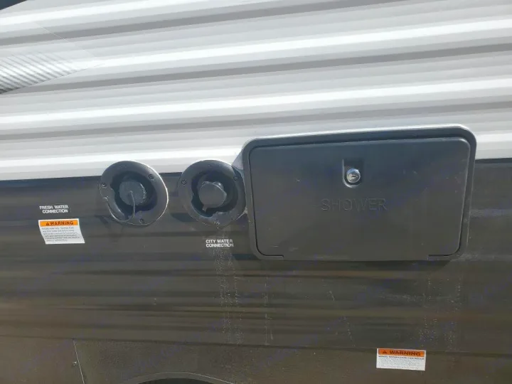 RV rental exterior: fresh water, city water connections & an outdoor shower unit are visible for campsite hookups.. Keystone RV Hideout 2021