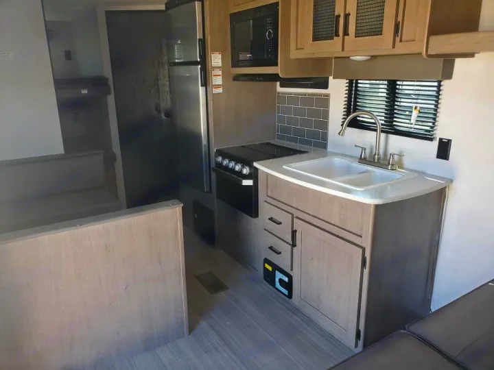 Explore this RV rental's interior: a full kitchen with double sink, stove, fridge, plus dinette & bunk beds.. Keystone RV Hideout 2021