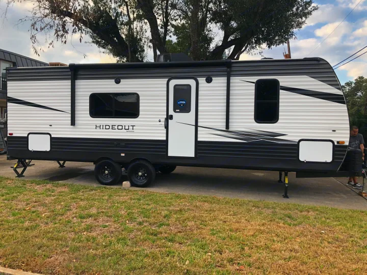 This sleek black and white Hideout travel trailer RV rental is parked outdoors, ready for adventure with its stabilizer jacks.. Keystone RV Hideout 2021