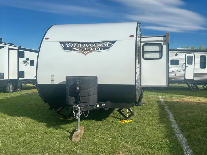 Forest River Wildwood X-Lite travel trailer for rv rental, among other campers on display in a sunny field.. Forest River Wildwood X-Lite 2022