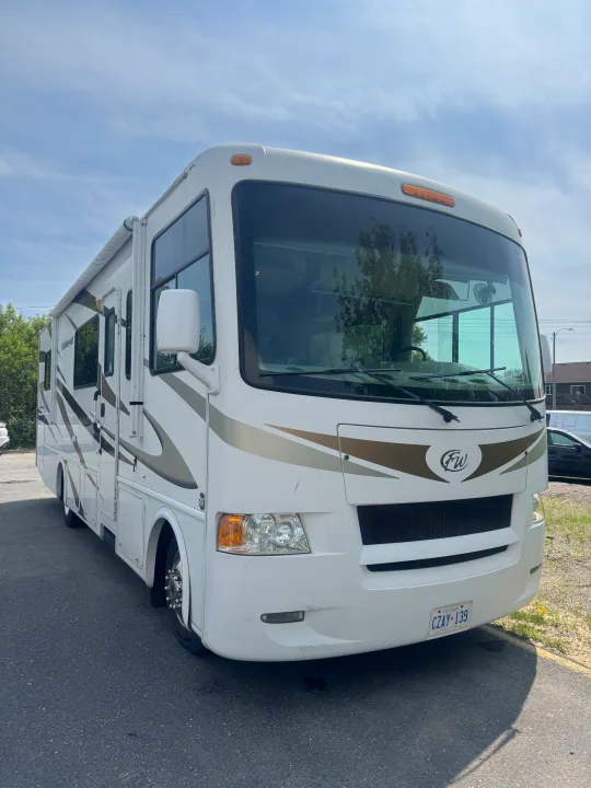 White Class A RV rental, a Thor Hurricane motorhome, parked on asphalt. Front and side visible.. Hurricane F53 2010
