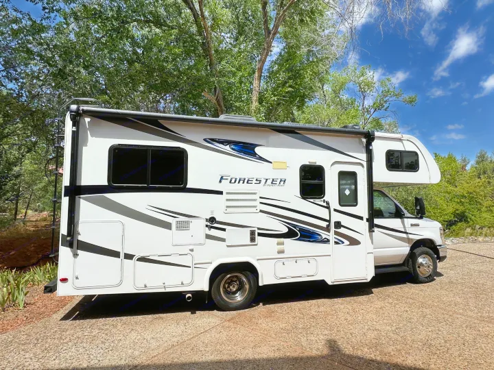 "Forester" Class C RV rental, a white motorhome with black & blue decals, parked on a sunny day. Ideal for camping & travel.. Forest River Forester Classic 2291S 2020