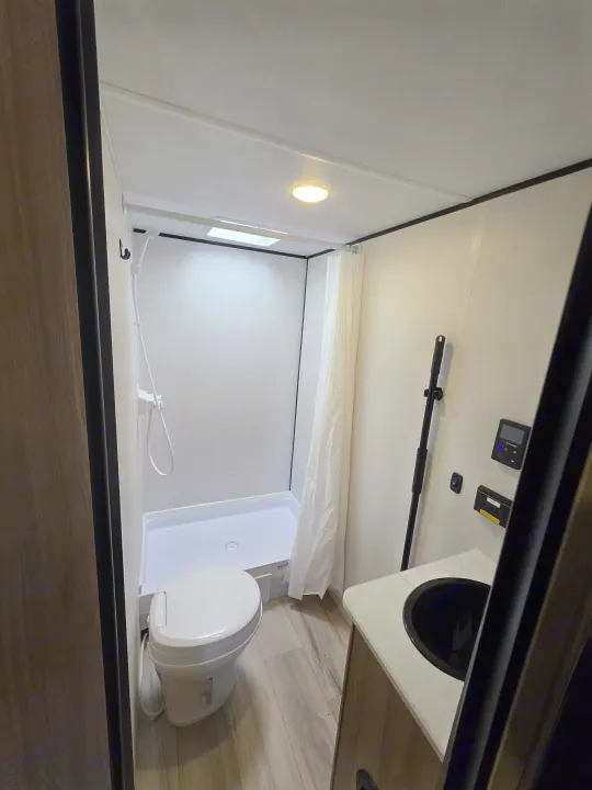 Clean and compact RV rental bathroom with a standing shower, toilet, and vanity sink, perfect for on-the-go living.. Keystone Coleman 2025