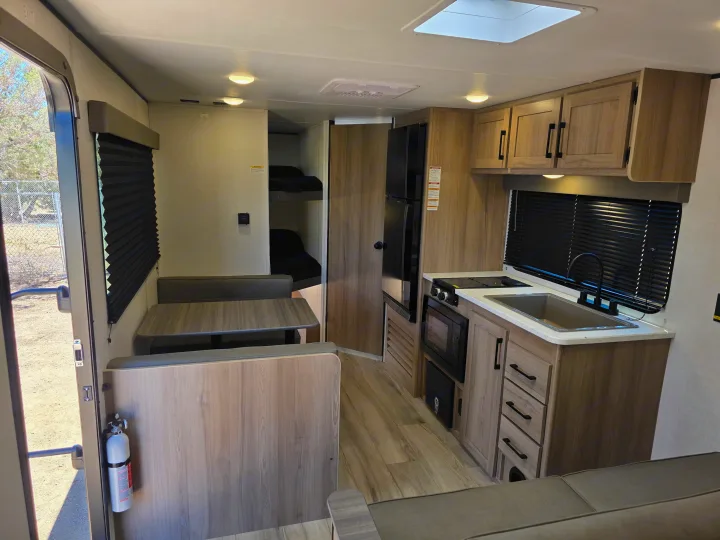 Explore this functional rv rental interior with a complete kitchen, dining area, and cozy bunk beds, ready for your next trip.. Keystone Coleman 2025