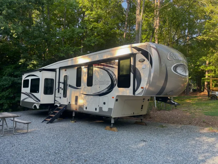 Columbus fifth-wheel RV rental parked on a gravel campground site, with slide-outs extended and a picnic table nearby.. 4x4fcmp23h6007284 Columbus 2017